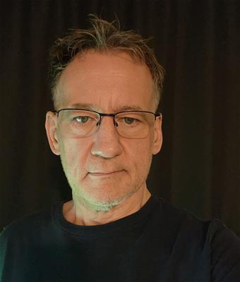 A person wearing glasses and a black shirt

Description automatically generated
